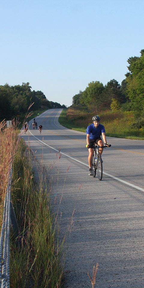 Bicyclists riding down a paved county road.